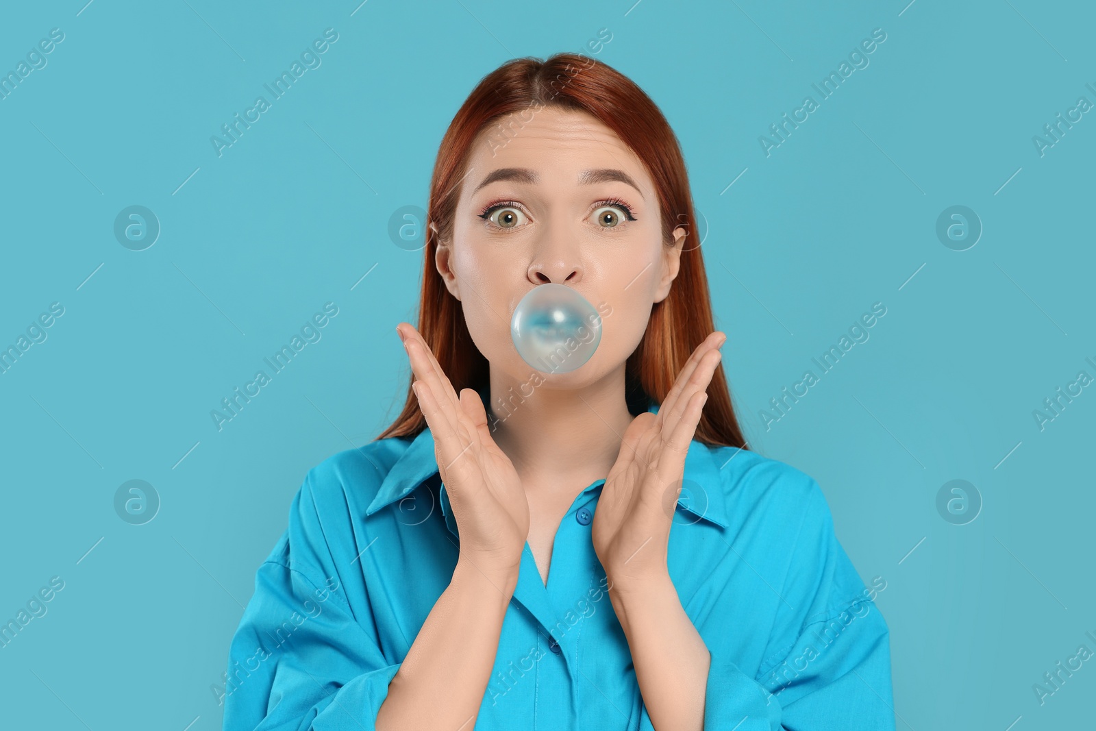 Photo of Surprised woman blowing bubble gum on turquoise background