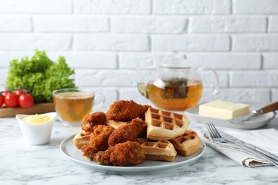 Photo of Tasty Belgian waffles served with fried chicken on white marble table