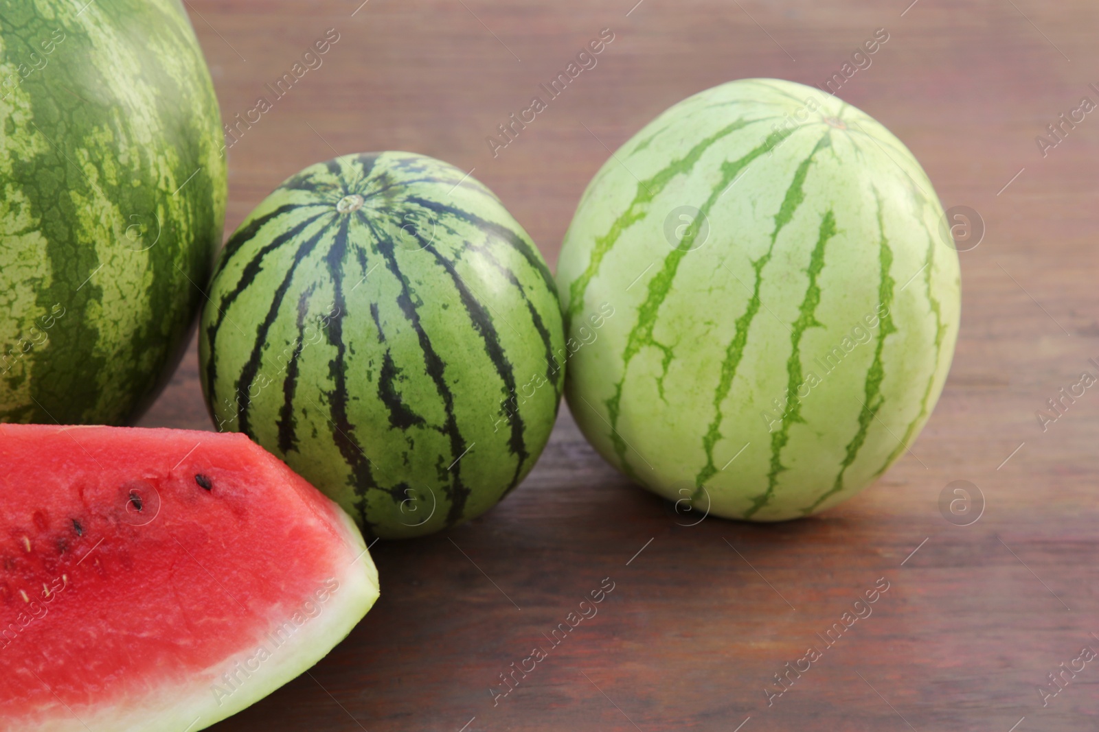 Photo of Different delicious ripe watermelons on wooden table