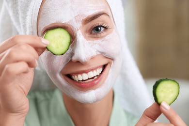 Photo of Woman with face mask and cucumber slices on blurred background, closeup. Spa treatments