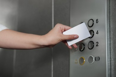 Woman choosing floor with card in elevator, closeup view. Protective measure
