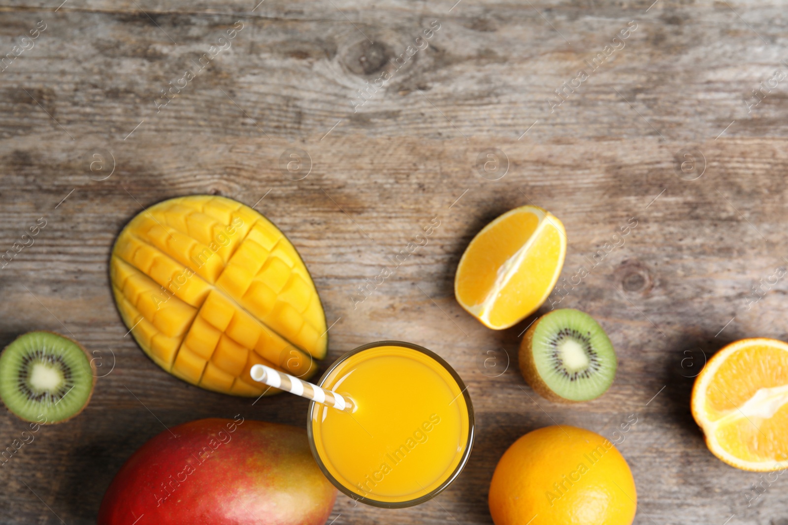 Photo of Glass with fresh mango juice and tasty fruits on wooden table, flat lay. Space for text