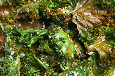 Photo of Tasty baked kale chips as background, closeup