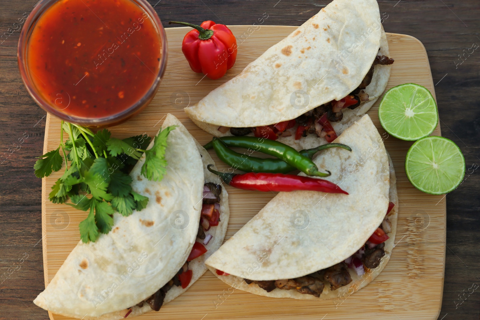 Photo of Delicious tacos with meat and vegetables on wooden table, top view