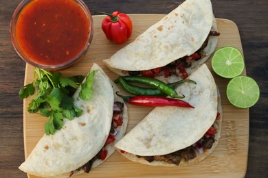 Delicious tacos with meat and vegetables on wooden table, top view