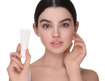 Photo of Teenage girl holding tube of foundation on white background