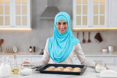 Portrait of Muslim woman near tray with cookies at white table in kitchen