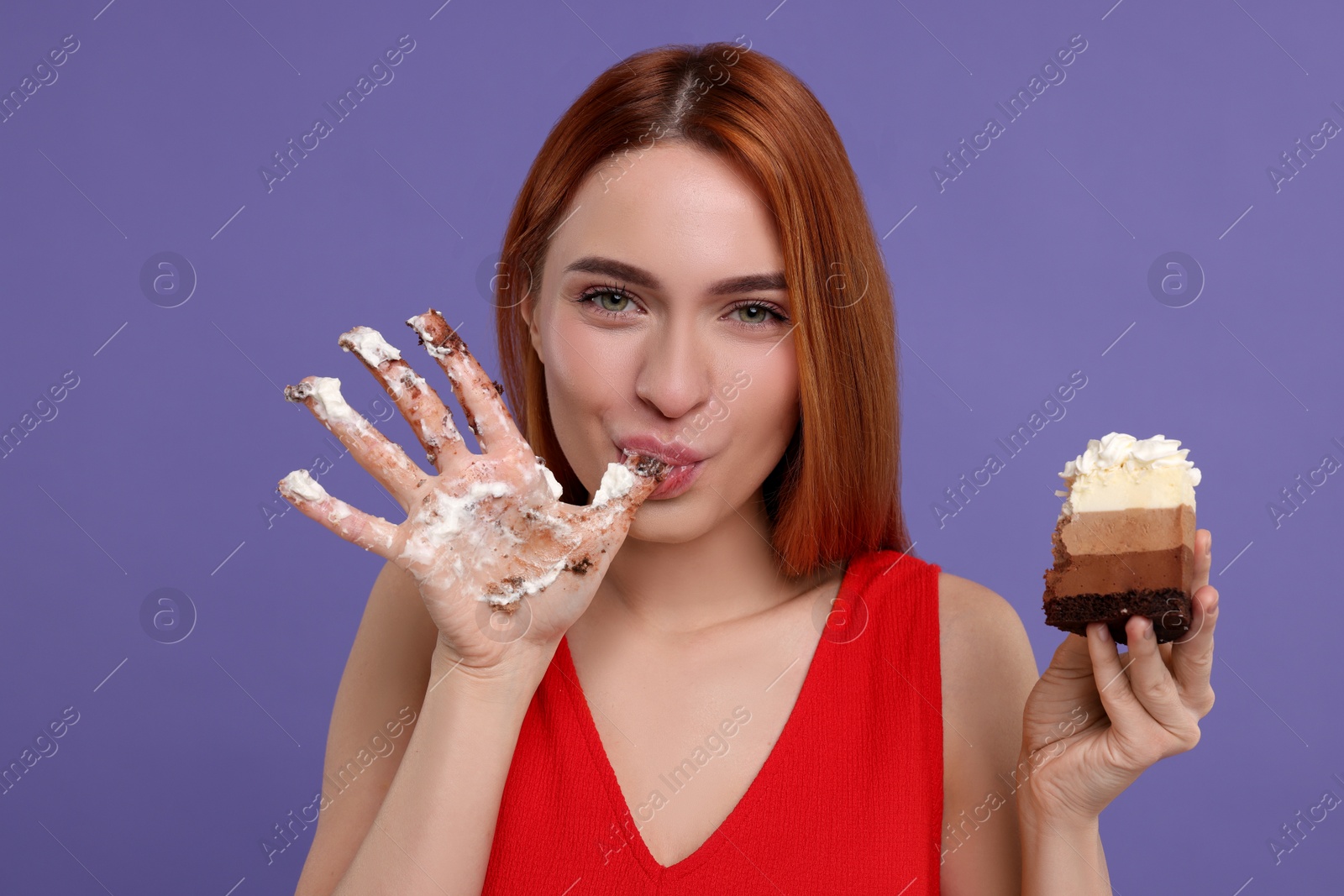 Photo of Young woman eating piece of tasty cake on purple background