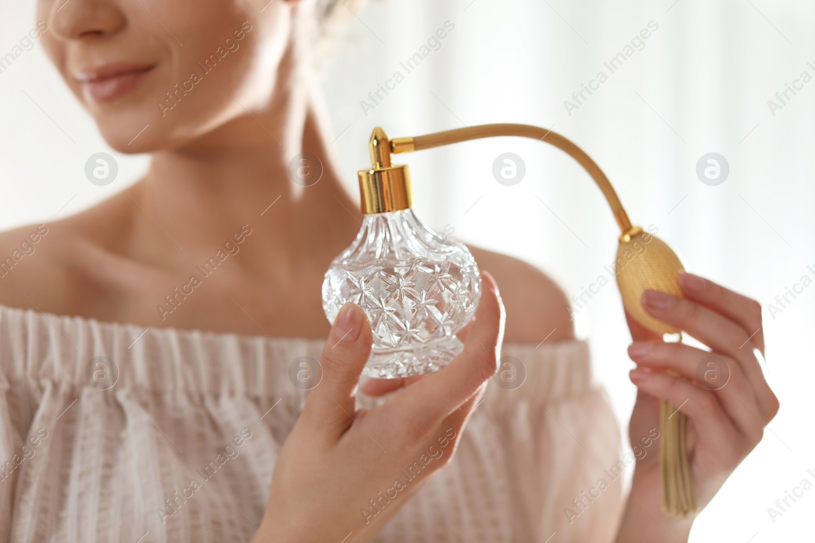 Photo of Young woman with bottle of perfume on blurred background, closeup