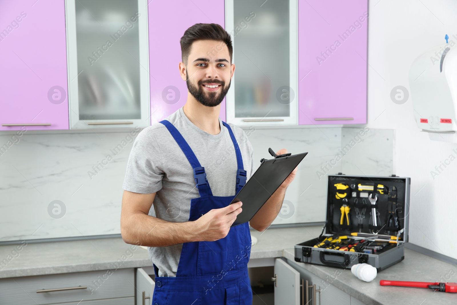 Photo of Male plumber with clipboard in kitchen. Repair service