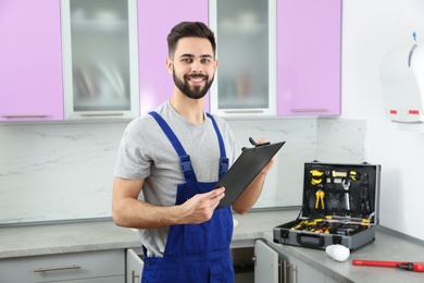 Photo of Male plumber with clipboard in kitchen. Repair service