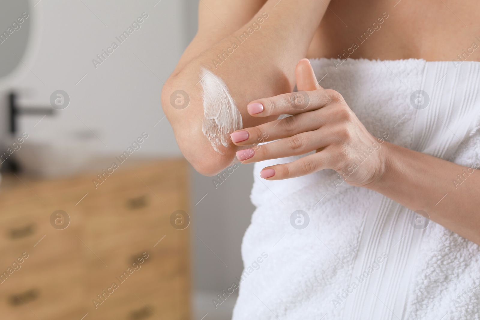 Photo of Woman applying body cream onto elbow indoors, closeup. Space for text