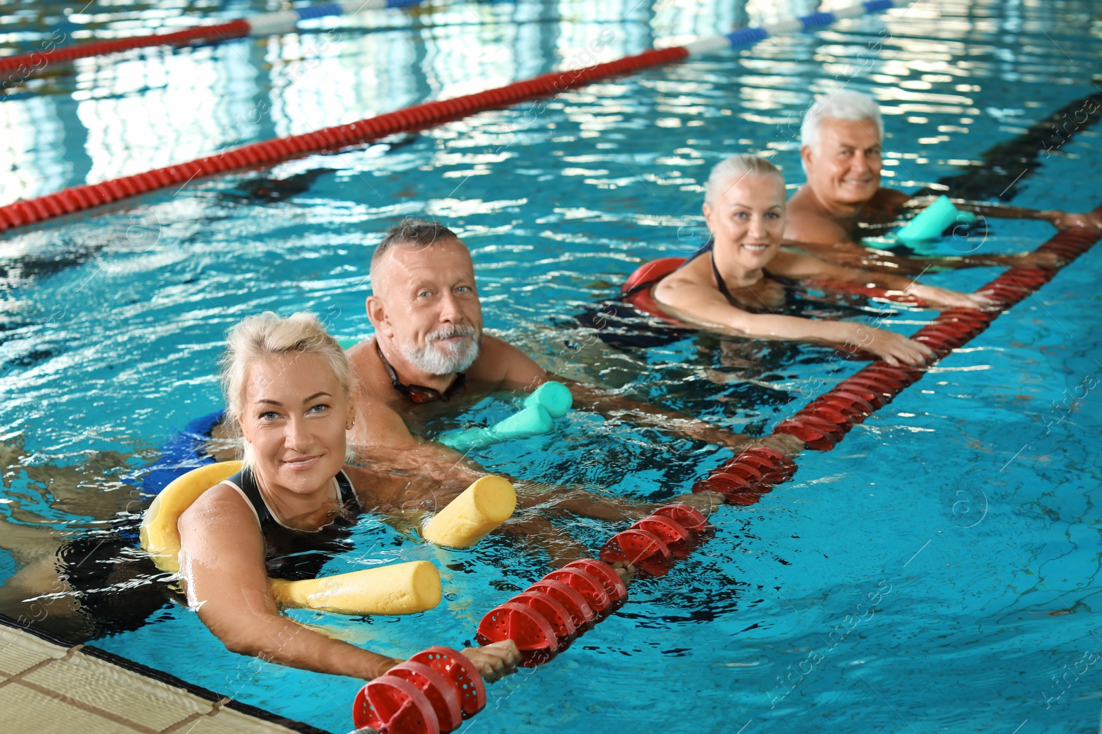 Photo of Sportive senior people doing exercises in indoor swimming pool