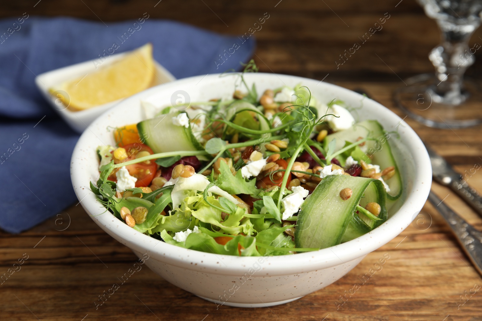 Photo of Delicious salad with lentils, vegetables and feta cheese served on wooden table