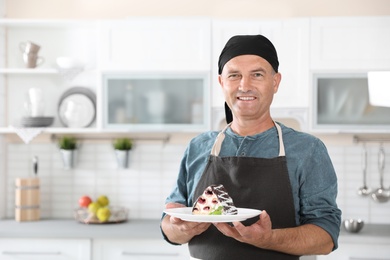 Photo of Professional male chef with plate of delicious dessert in kitchen
