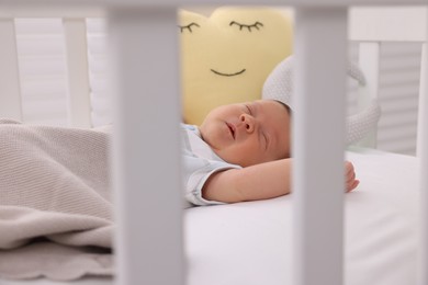 Cute newborn baby sleeping under blanket in crib at home
