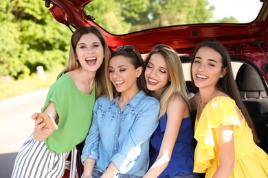 Happy beautiful young women taking selfie near car