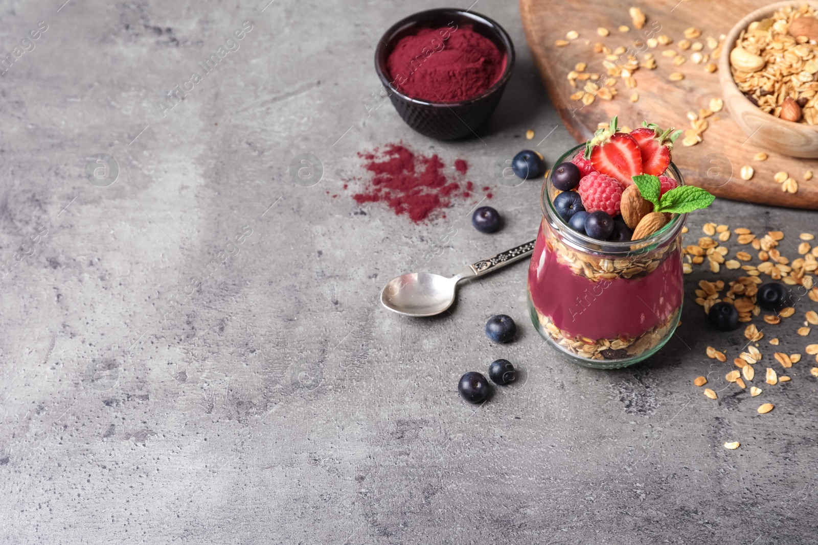 Photo of Delicious acai dessert with granola and berries served on grey table. Space for text