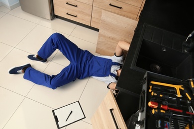 Photo of Male plumber repairing kitchen sink, above view