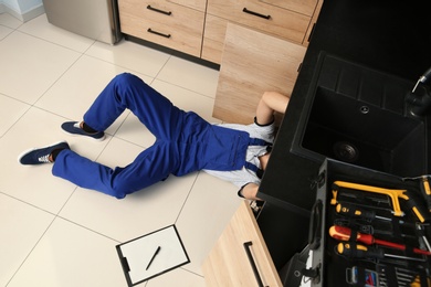 Male plumber repairing kitchen sink, above view