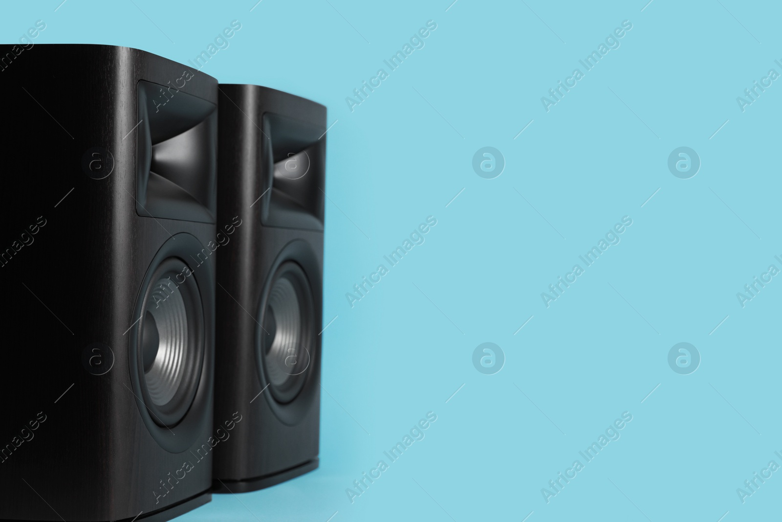 Photo of Wooden sound speakers on light blue background. Space for text