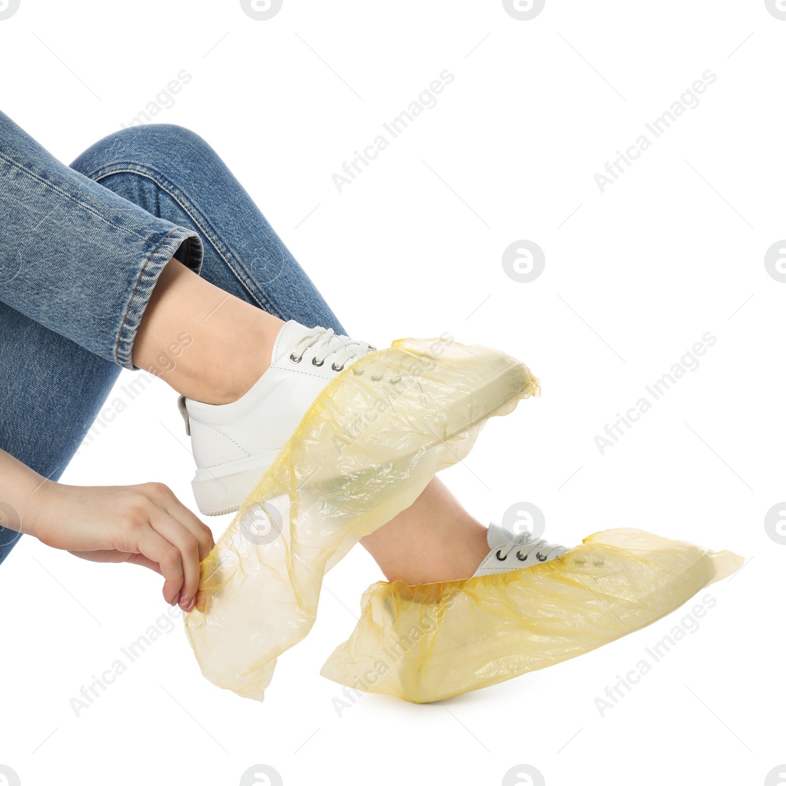 Photo of Woman wearing yellow shoe covers onto her sneakers against white background, closeup