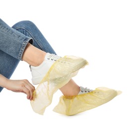 Photo of Woman wearing yellow shoe covers onto her sneakers against white background, closeup