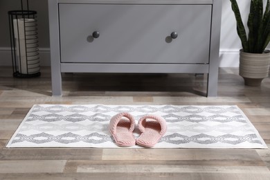 Photo of Mat with slippers near grey chest of drawers in bathroom