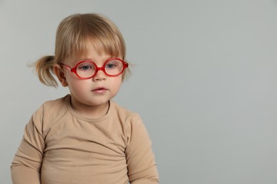 Cute little girl in glasses on light grey background. Space for text