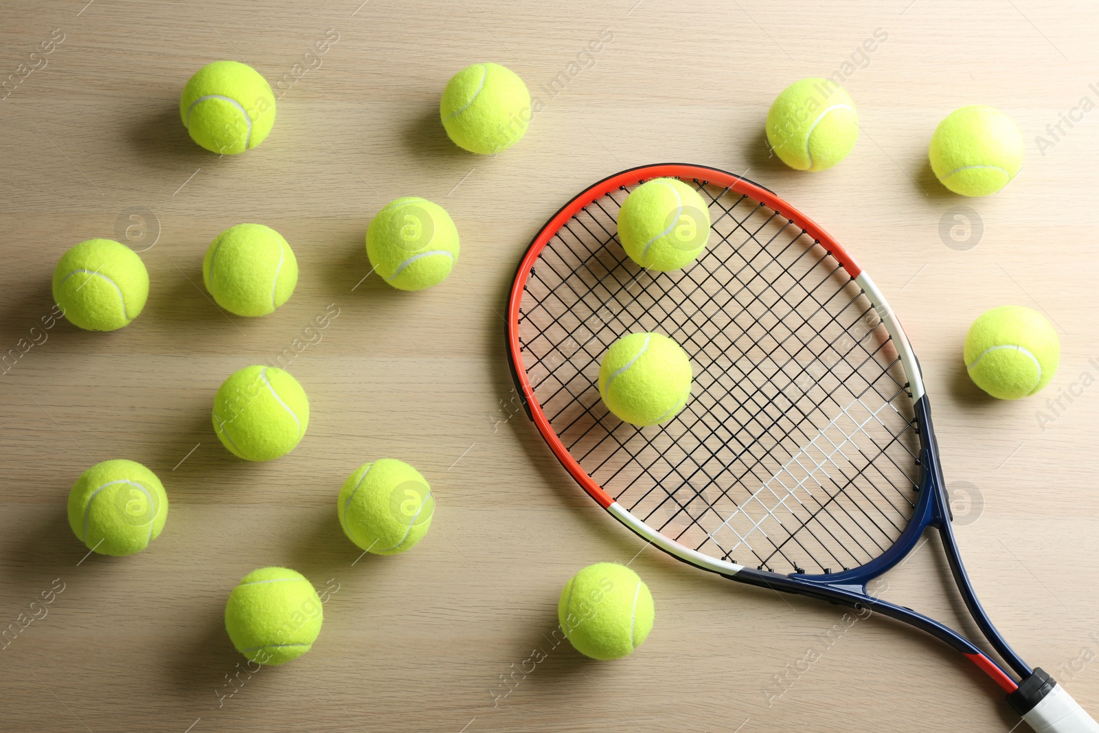 Photo of Tennis racket and balls on wooden table, flat lay. Sports equipment