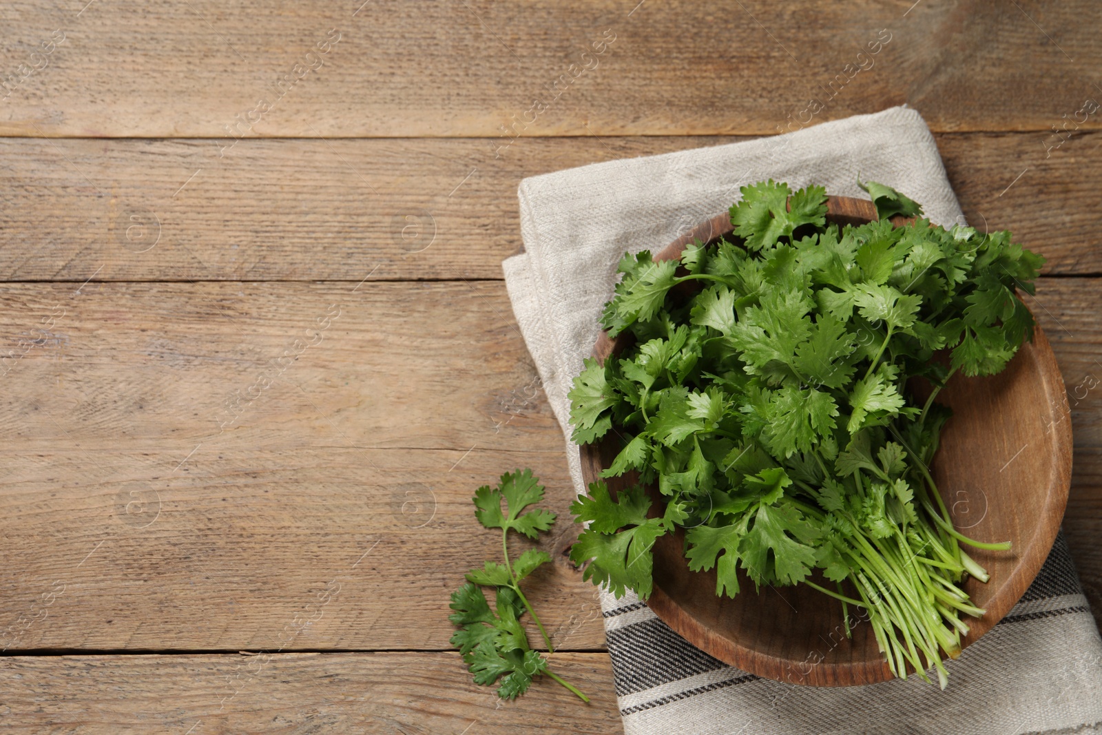 Photo of Bunch of fresh aromatic cilantro on wooden table, flat lay. Space for text