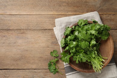 Photo of Bunch of fresh aromatic cilantro on wooden table, flat lay. Space for text
