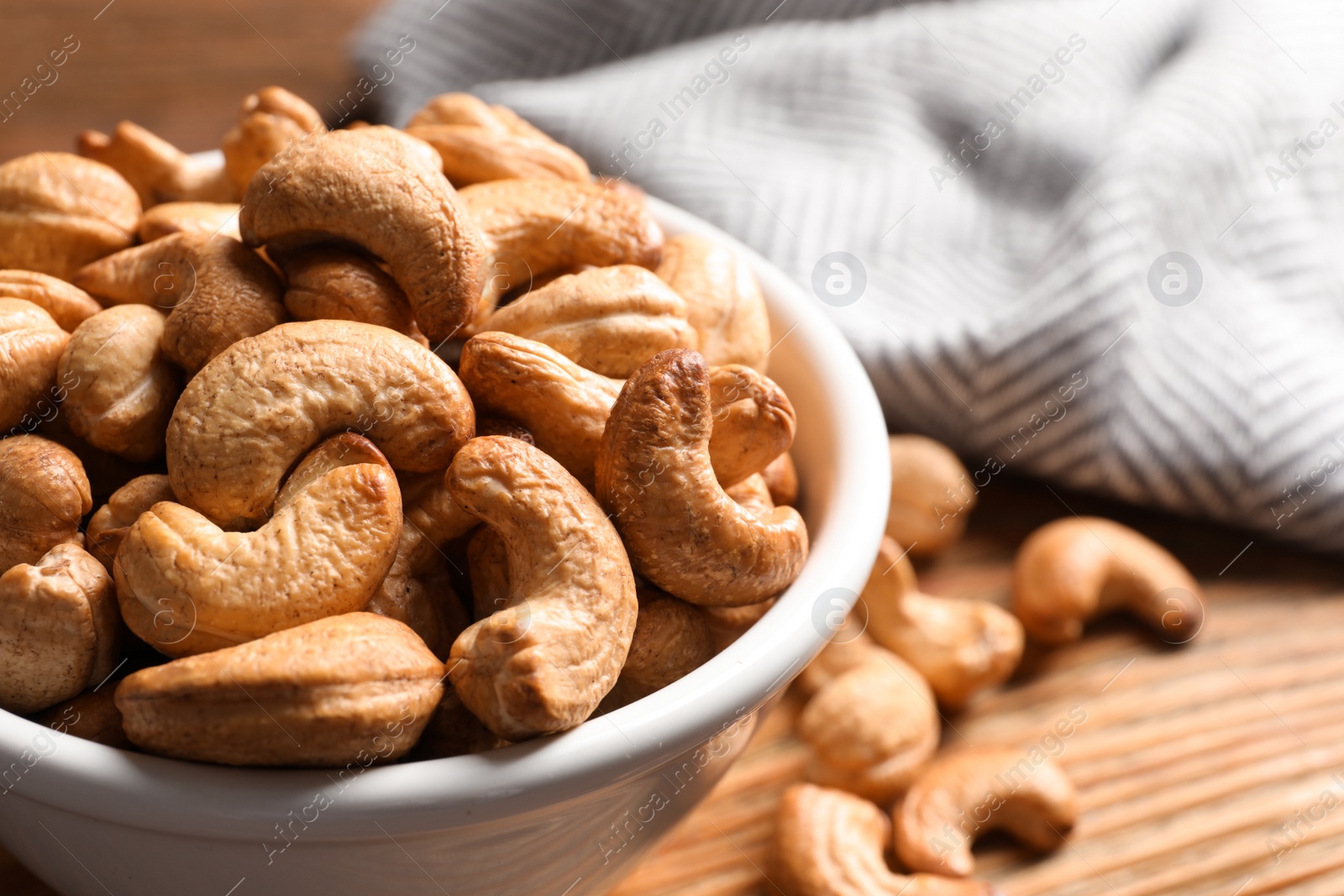 Photo of Tasty cashew nuts in bowl on table, closeup