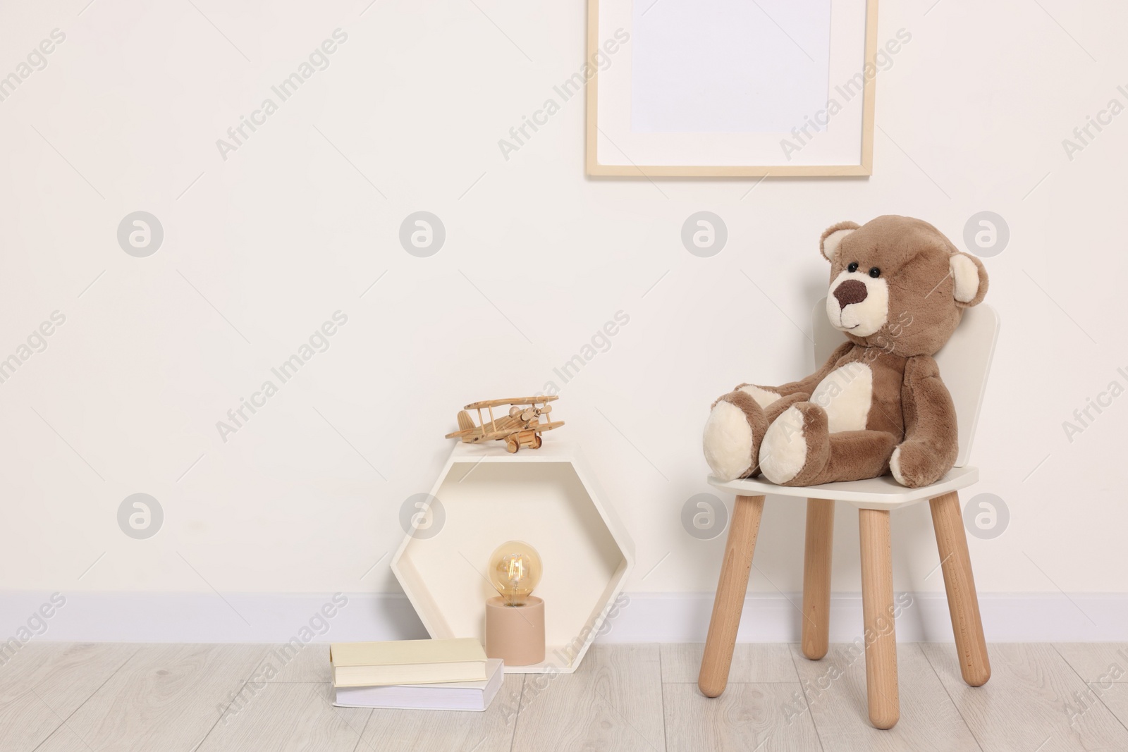 Photo of Beautiful children's room with light wall, furniture and toys. Interior design