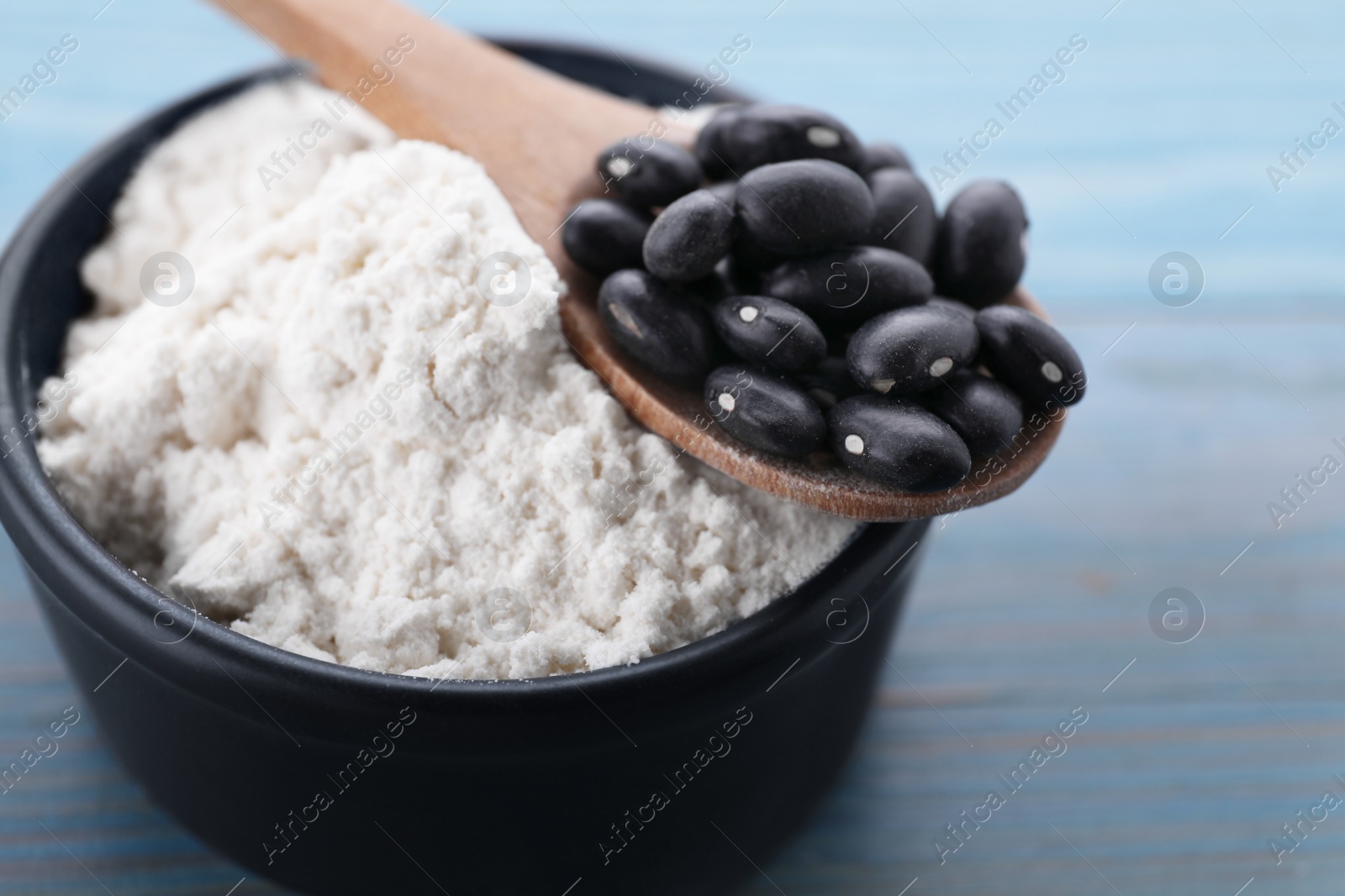 Photo of Kidney bean flour and black seeds on light blue wooden table, closeup