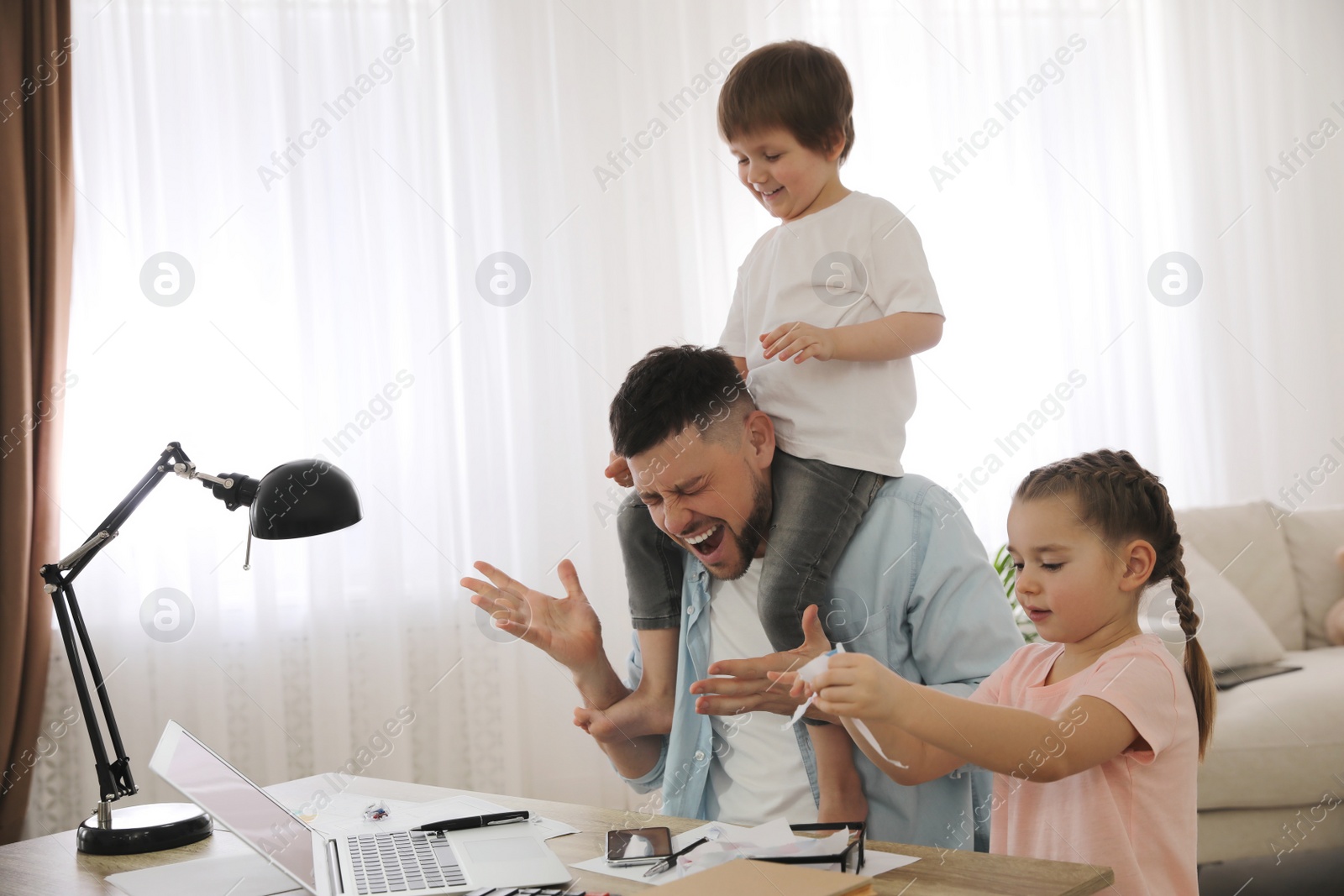 Photo of Overwhelmed man combining parenting and work at home