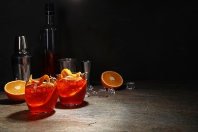 Photo of Aperol spritz cocktail, ice cubes and orange slices in glasses on grey textured table, space for text