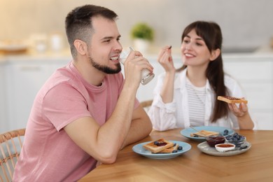 Happy couple having tasty breakfast at home