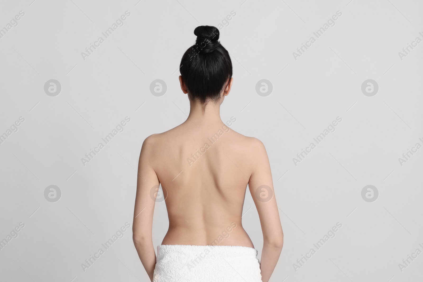 Photo of Back view of woman with perfect smooth skin on light background