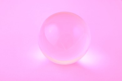 Photo of Transparent glass ball on light violet background