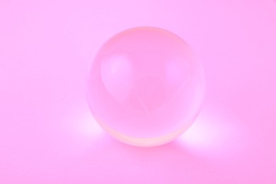 Transparent glass ball on light violet background