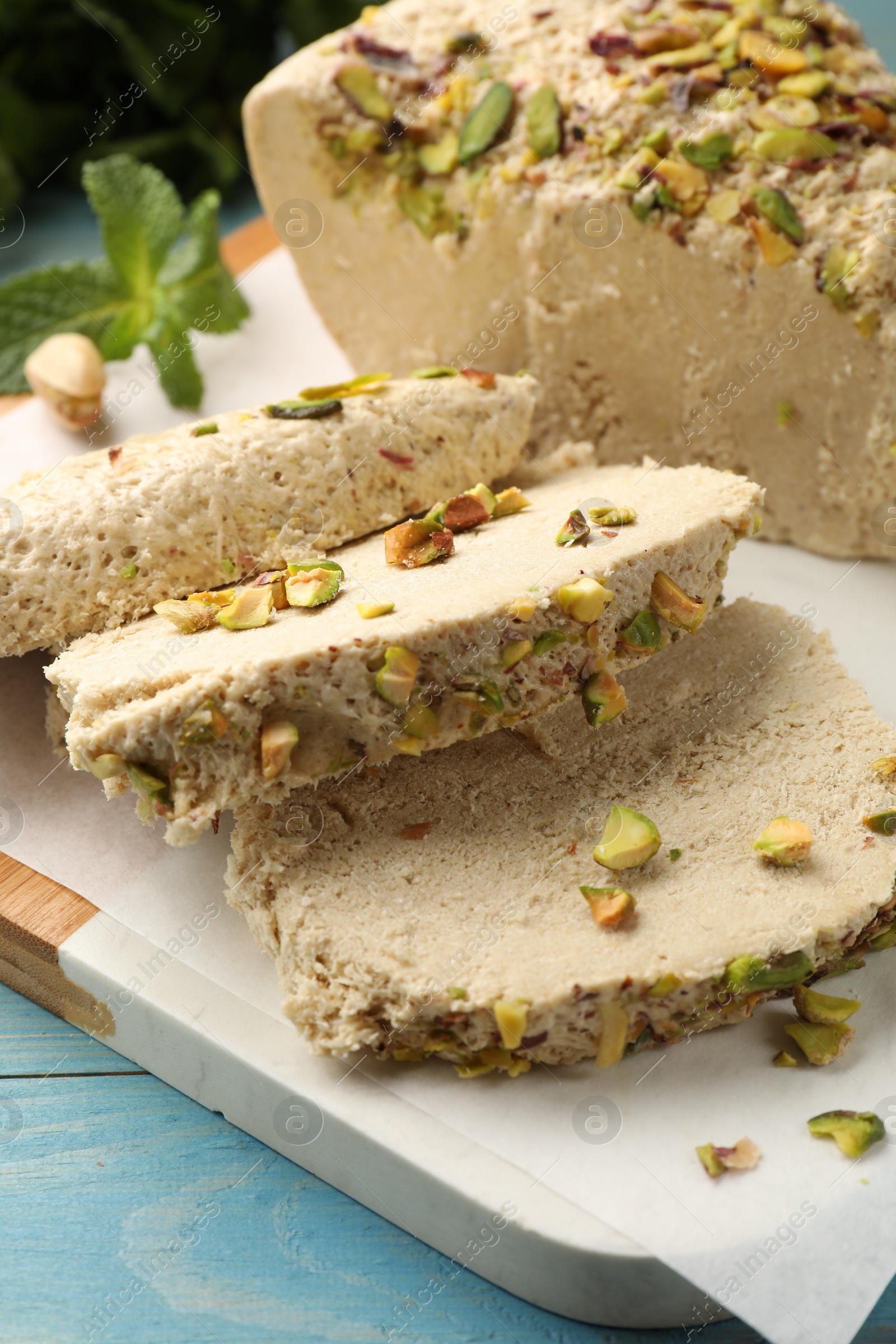 Photo of Pieces of tasty halva with pistachios on table, closeup