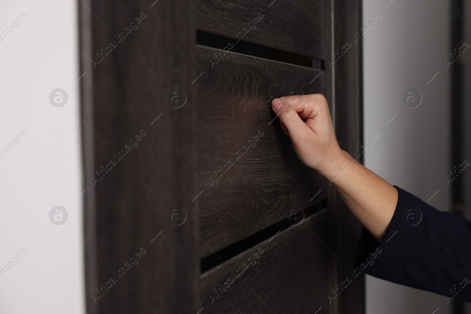 Photo of Collector knocking on door indoors, closeup view