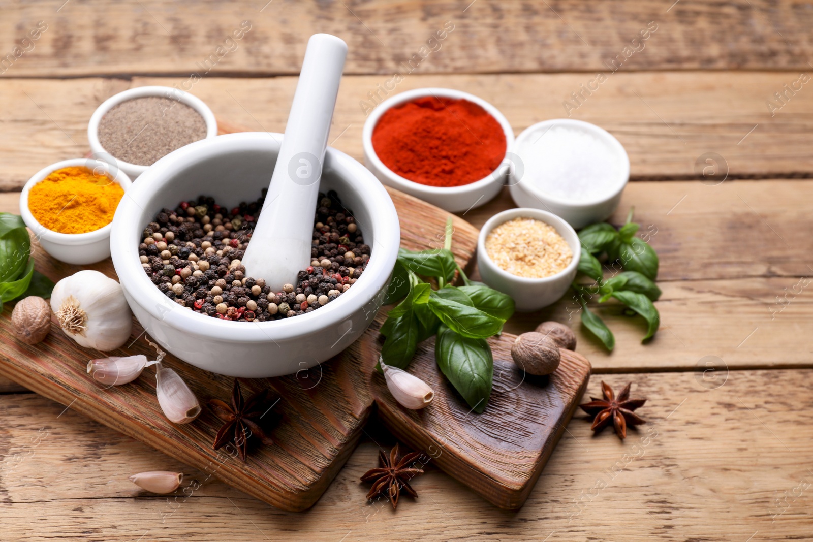 Photo of Mortar with pestle and different spices on wooden table