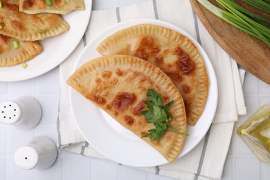 Photo of Delicious fried cheburek with cheese and parsley on white tiled table, flat lay