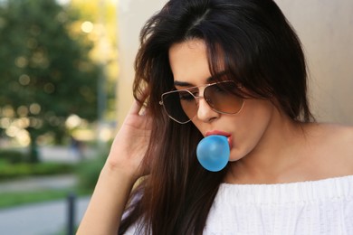 Photo of Beautiful woman in sunglasses blowing gum outdoors