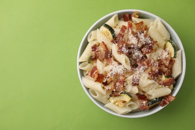 Photo of Tasty pasta with bacon and cheese on light green table, top view. Space for text