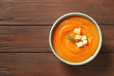 Bowl of tasty sweet potato soup on wooden background, top view. Space for text