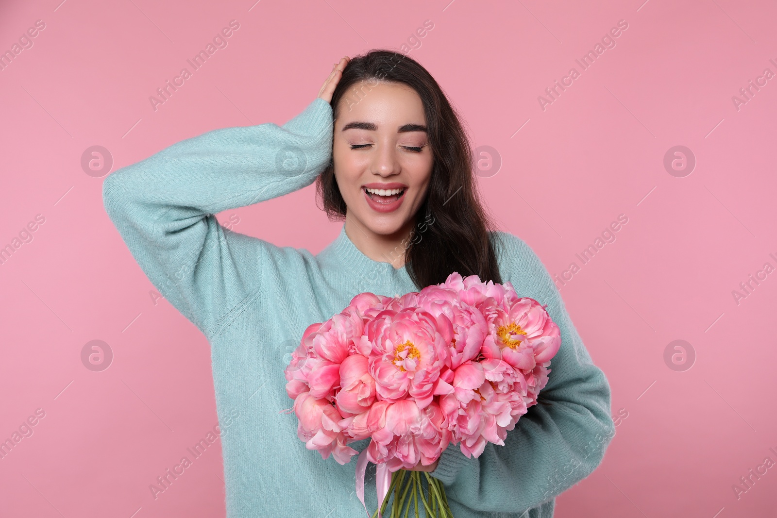 Photo of Beautiful young woman with bouquet of peonies on pink background