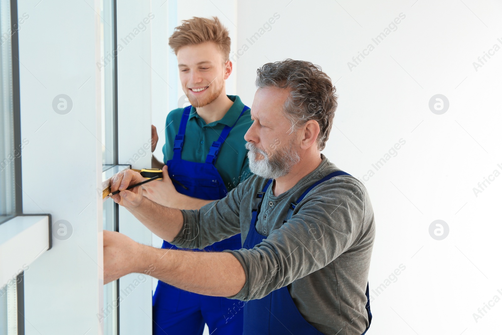 Photo of Service men measuring window for installation indoors